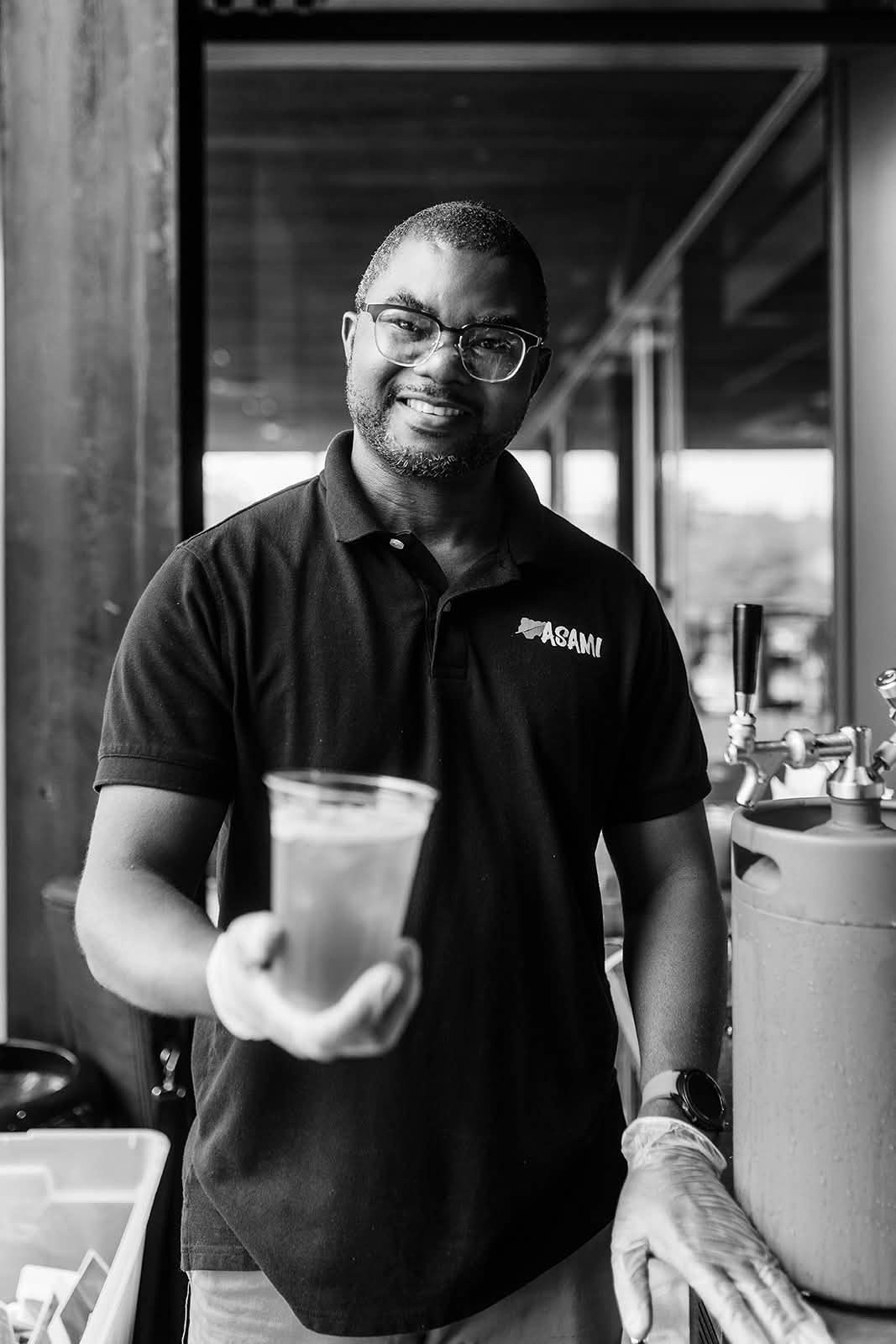 A smiling vendor holding out a drink at his Expo booth